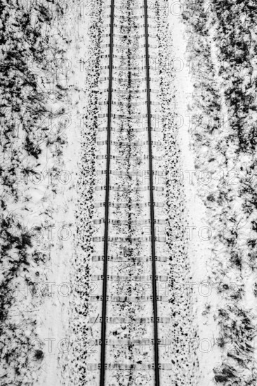 A railroad track in winter surrounded by snow, black and white photography Germany