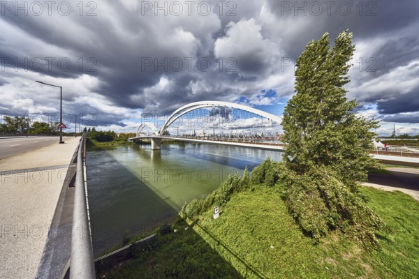 Europe bridge, car and pedestrian bridges, Beatus Rhenanus bridge, pedestrian and tram bridge, architect Marc Barani, Rhine river, border between Germany and France, sidewalk, cycle path, street, lantern, metal railing, trees, meadow, rainy mood, blue partly cloudy sky, cumulus congestus clouds, image processing brightnesses and contrasts, Strassburger Straße, Kehl, Upper Rhine Plain, Ortenaukreis, Baden-Württemberg, Germany
