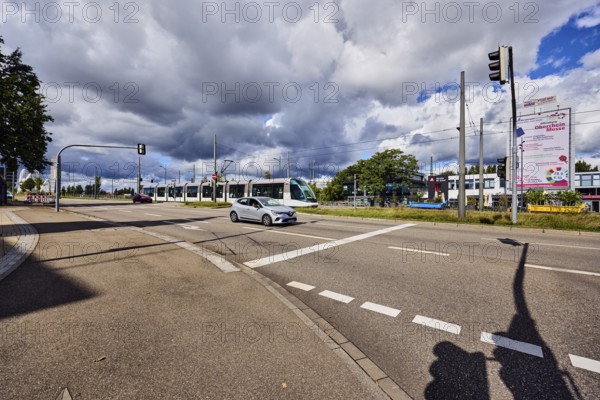 Tram, cars, street, sidewalk, lanes, cycle path, catenary masts, overhead line, central island, trees, meadow, blue sky, cumulus clouds, cumulus congestus clouds, confluence of main street in Strassburger Straße, Kehl, Upper Rhine Valley, Ortenau district, Baden-Württemberg, Germany