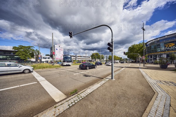 Traffic light crossing, general architecture, train station, sidewalk, cycle path, road, cars, coach, meadow, trees, blue partly cloudy sky, cumulus clouds, cumulus congestus clouds, confluence of main street in Strassburger Straße, Kehl, Upper Rhine Plain, Ortenaukreis, Baden-Württemberg, Germany