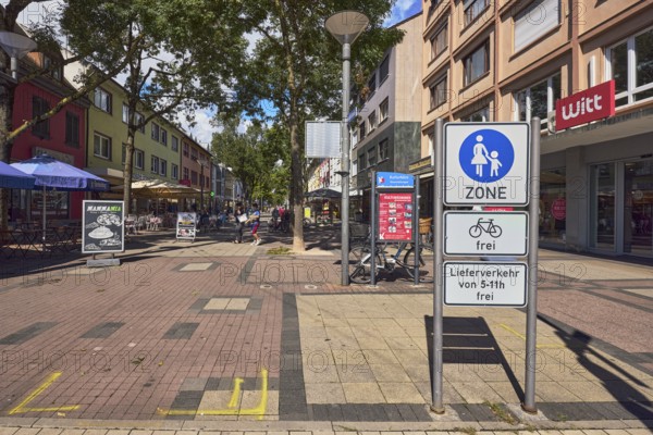 Pedestrian zone, traffic sign pedestrian zone with additional sign bicycles free and delivery traffic of 5-11 h free, lantern, general architecture, commercial buildings, residential and commercial buildings, shops, shopping, retail, outdoor area of a restaurant, pedestrians as accessories, city trees, blue sky, cumulus clouds, main street, Kehl, Upper Rhine plain, Ortenau district, Baden-Württemberg, Germany