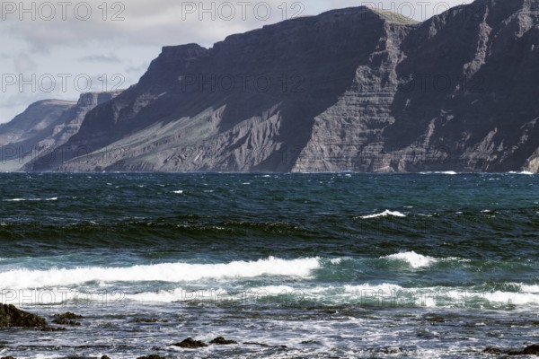 Coast with thundering waves and high mountains in the background Risco de Famara) under partly cloudy sky, Playa Caleta de Famara, Teguise Lanzarote