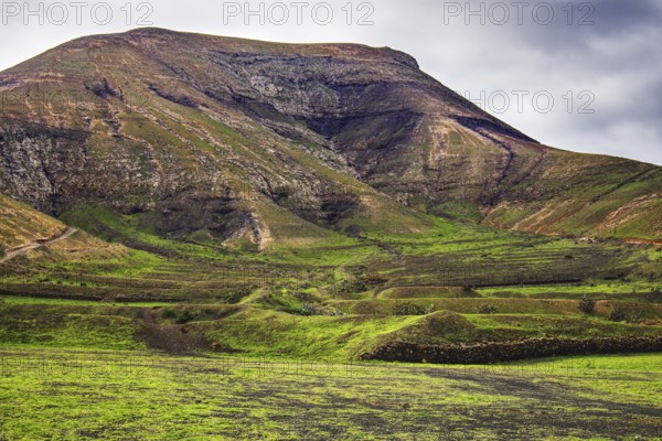 Green hills and mountain landscape under a cloudy sky, Yaiza Lanzarote