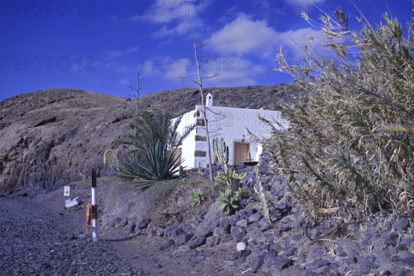 Lonely house in a barren volcanic landscape under a clear blue sky, Playa Quemada, Yaiza Lanzarote