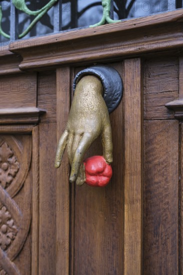 A cast iron door knocker on a wooden, artfully decorated front door in the shape of a hand holding a fruit, art nouveau, bushel castle, Mettnau peninsula, Radolfzell am Lake Constance, district of Constance, Baden-Württemberg, Germany