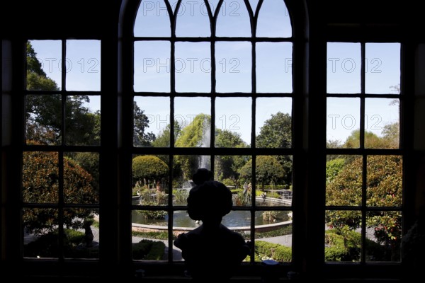 View through a window of a well-kept garden with a bust in the foreground, zero