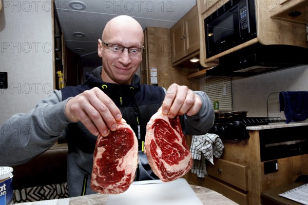 A man in an RV holds two large steaks in Middletown, Middletown, USA