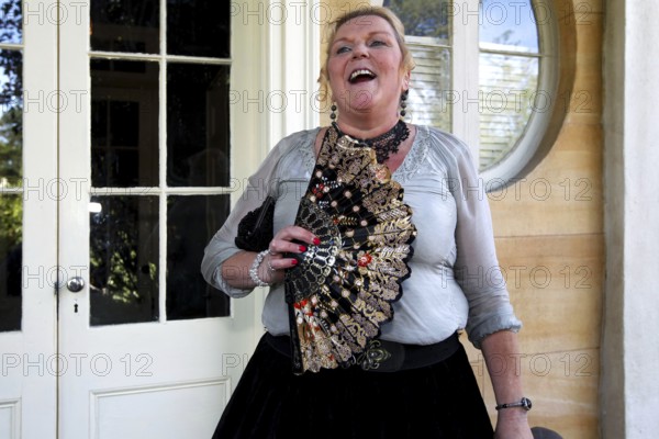 Laughing woman with decorative fan standing in front of an elegant entrance, Houmas House, Louisiana, USA