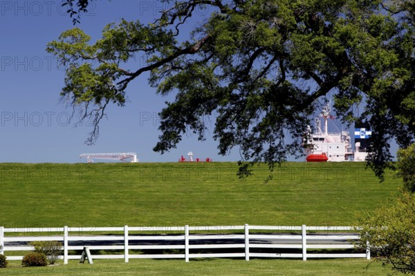 Green dike with fence and part of a ship visible, Mississippi Valley, USA