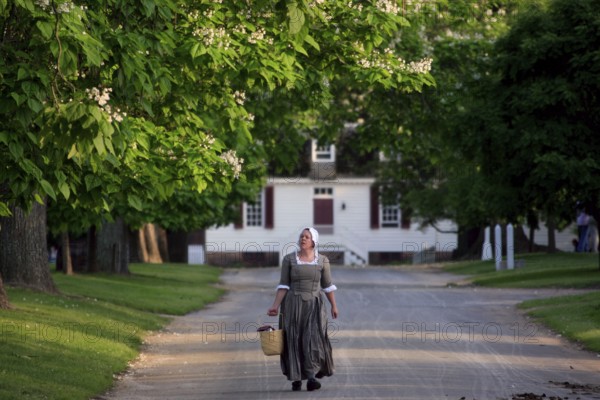 Woman wearing historical costume on a tree-lined street in Colonial Williamsburg, Williamsburg, Virginia, USA