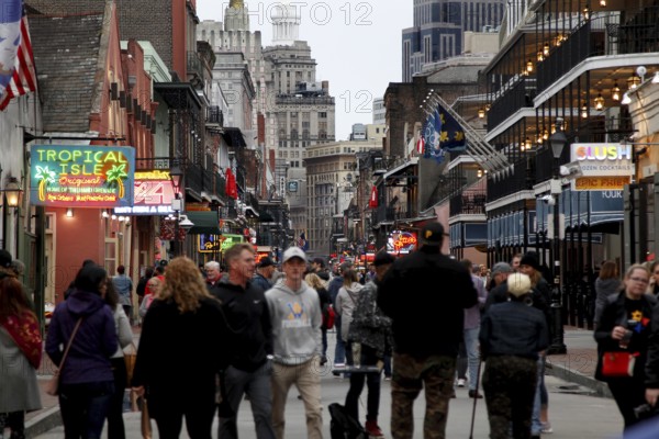Bustling Bourbon Street at night with numerous passers-by and illuminated signs, New Orleans, Louisiana, USA