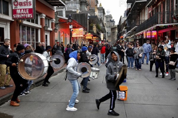 Musicians play on bustling Bourbon Street in the French Quarter. Drums and people create a lively atmosphere, New Orleans, Louisiana, USA