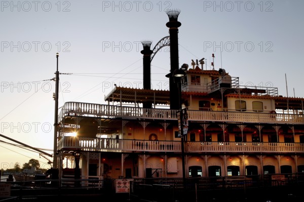 A paddle steamer on the River Front, illuminated at dusk in New Orleans, New Orleans, Louisiana, USA