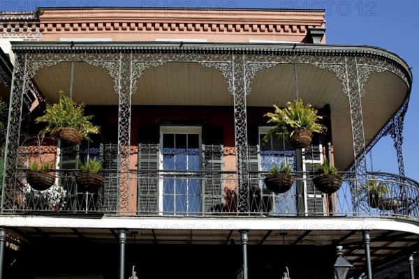 Colonial balcony with decorated ironwork and hanging plants in the French Quarter, New Orleans, Louisiana, USA