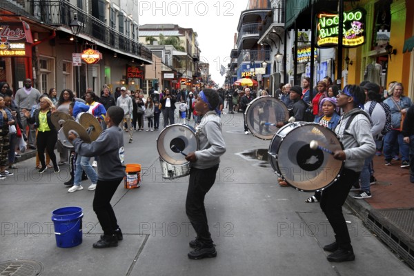 Musicians play drums on Bourbon Street as passers-by flock around them, New Orleans, Louisiana, USA