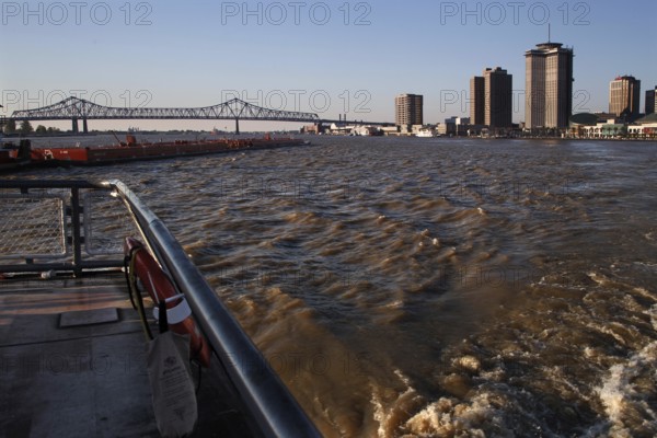 View of Mississippi River with skyscrapers and bridge at sunset, New Orleans, Louisiana, USA