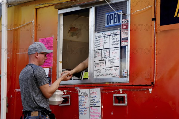 Person orders food from a colorful food truck full of menu boards, Natchez, Mississippi, USA