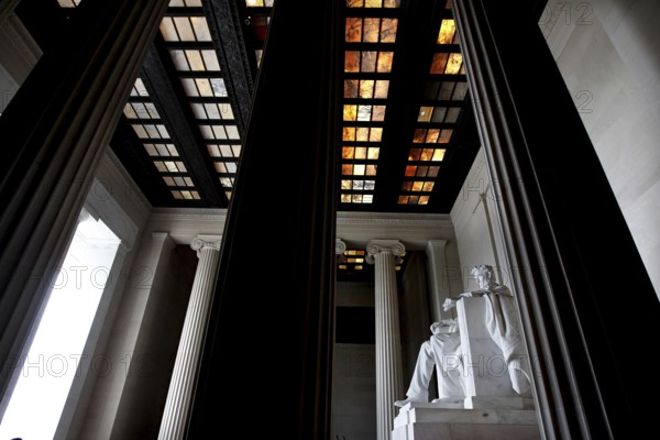 Monumental statue of Abraham Lincoln between tall pillars in a monumental building, Washington D.C, USA
