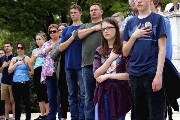 Group of people standing with hands on their hearts in a respectful and serious gesture, Washington D.C, USA