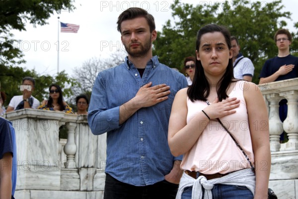 A man and a woman stand respectfully with their hands on their hearts during a ceremony, Washington D.C, USA