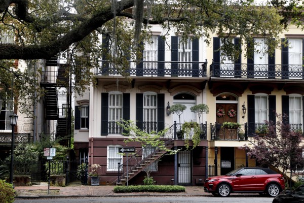 Historic townhouse with balconies and a red car in front of it in Savannah, Savannah, Georgia, USA