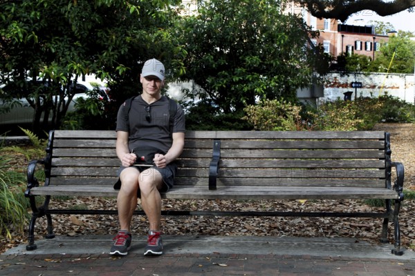 A man sits alone on a bench in Chippewa Square enjoying the park, Savannah, Georgia, USA