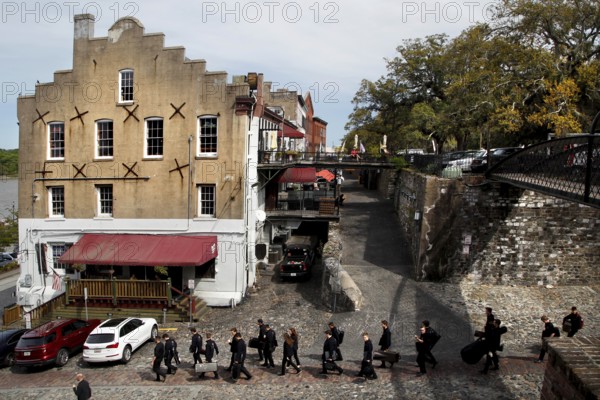 Buildings along Factors Walk with paved road and walkers, Savannah, Georgia, USA