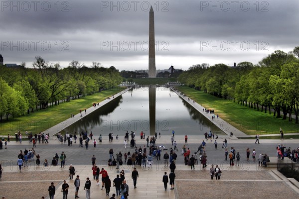 Visitors look at the Washington Monument across a reflecting pond, Washington D.C, USA