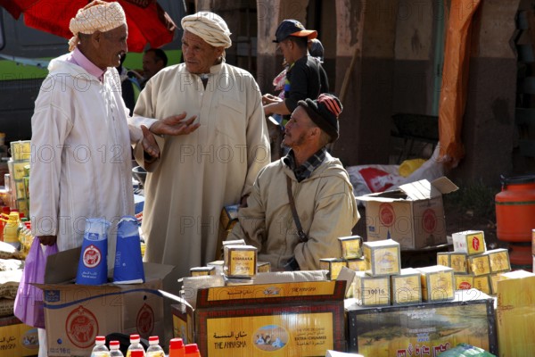 Market scene with men talking in front of a variety of products, Msemrir, Region, MA