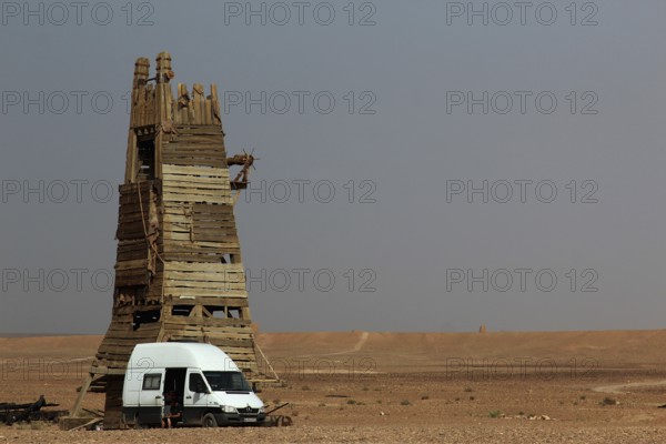 Desert scene with a tall rustic tower and a van in the foreground, Ouarzazate, Morocco