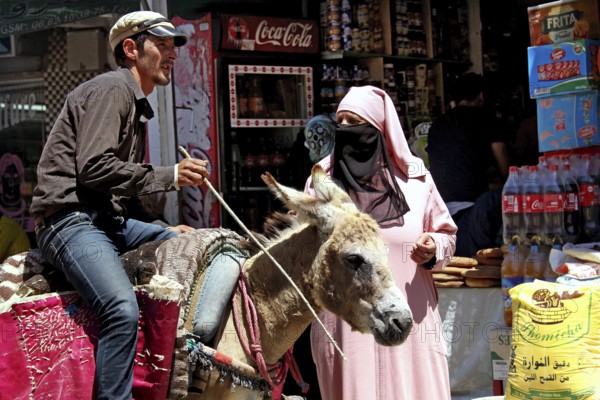 Market scene on Place Mohammed VI in Moulay Idris with a donkey and local inhabitants, Moulay Idris, Fès-Meknes, Morocco