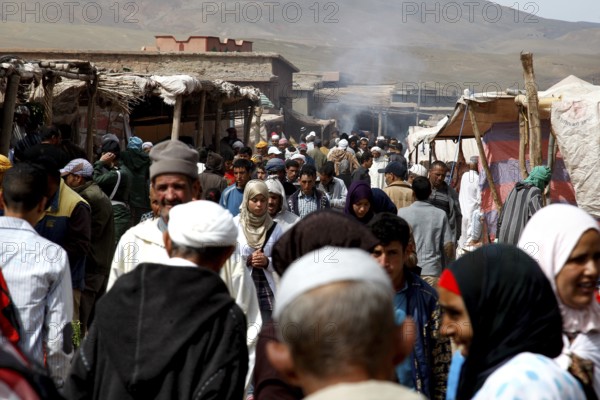 Bustling market in Msemrir with lots of people and stalls against a mountain backdrop, Msemrir, Morocco