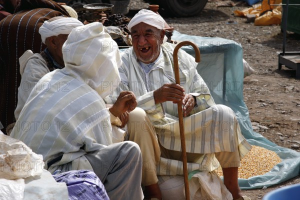 Men wearing traditional clothes talk at a market in Msemrir, Msemrir, Morocco