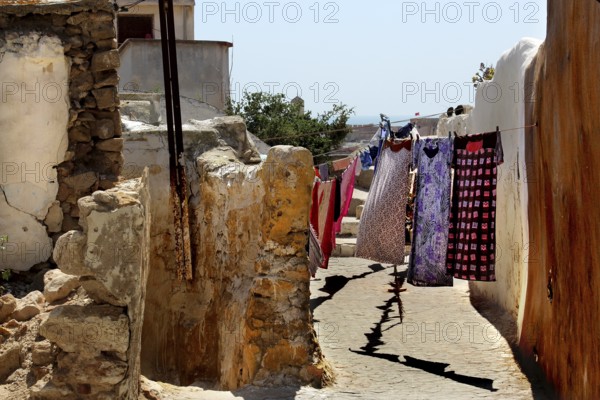 Narrow path between stone houses with colorful fabrics on clotheslines, Safi, Medina, Morocco