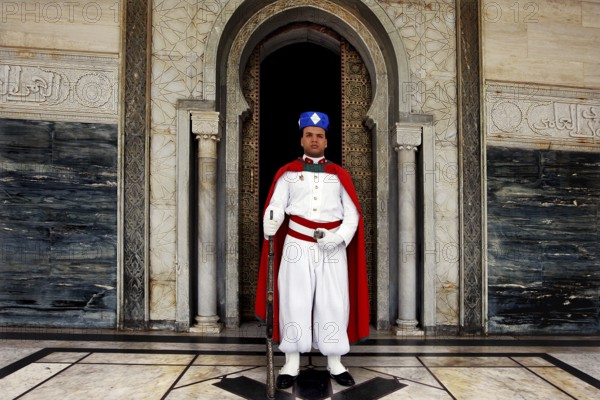 Guard in traditional uniform in front of the entrance to the Hassan Mausoleum, Rabat, Morocco