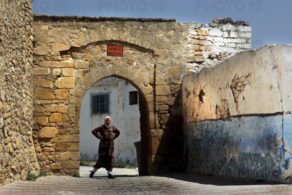 A man stands under an old stone arch in the medina of Safi, Safi, Doukkala-Abda, Morocco