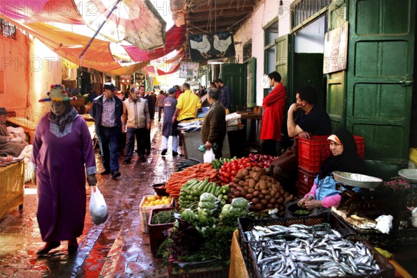A lively market scene with a variety of fresh vegetables and people passing by, Tetouan, Medina, Morocco