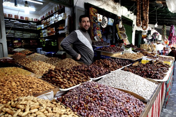 A vendor at a market stand offers a wide range of dates and dried fruits, Tetouan, Medina, Morocco