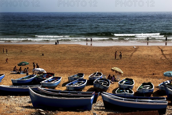 Blue fishing boats on beach with sea view and close people, Taghazout, Souss-Massa region, Morocco