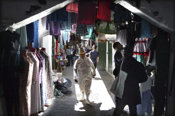 Market scene with colorful clothes and textiles hung in a narrow alley, Tetouan, Medina, Morocco