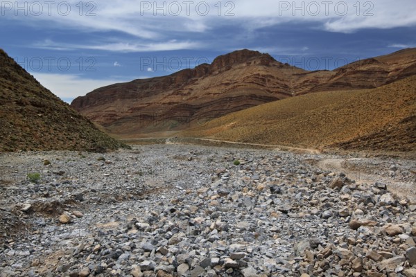 A dry, rocky landscape under a blue sky, valley, Tizgui n'Ouadda