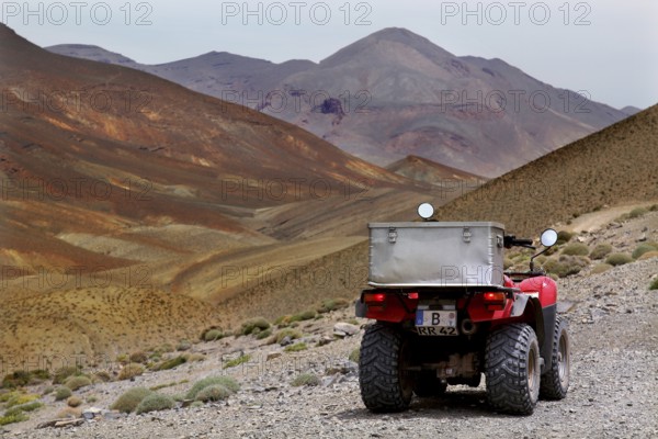 Quad on rocky road with surrounding mountain landscape and desert horizon, Tizgui n'Ouadda, Morocco
