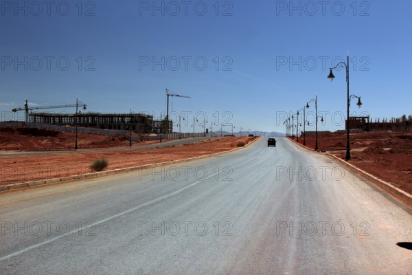 Lonely road with lanterns in dry desert environment under clear sky, Tinerhir, Morocco