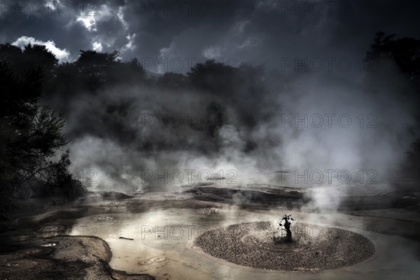 Steaming mud hole in dark, atmospheric surroundings in Wai-O-Tapu