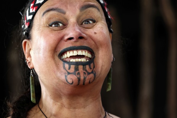 Smiling woman wearing a traditional Maori style moko, Rotorua, Whakarewarewa, New Zealand