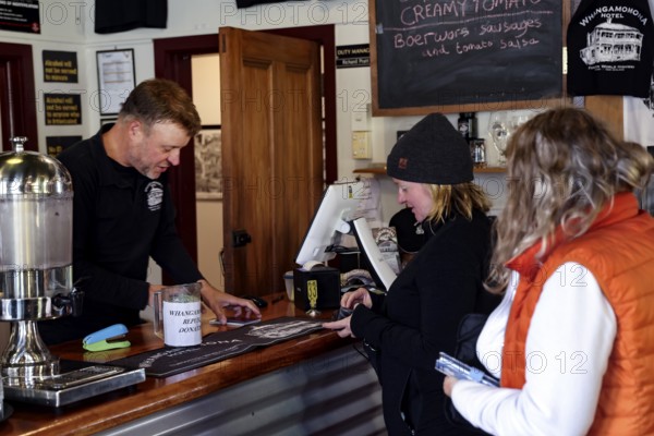 People at the Whangamomona Hotel communicating at reception in a cozy atmosphere, Whangamomona, New Zealand