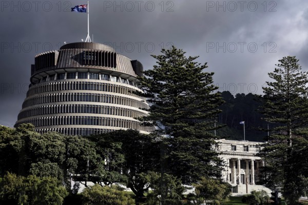 The parliament building 'Beehive' in Wellington surrounded by trees under a cloudy sky, Wellington, New Zealand