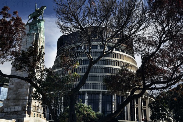 Parliament building in Wellington partly obscured by trees under clear skies, Wellington, New Zealand