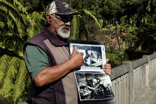 Man showing a book at the bridge in the thick forest on the Whanganui River, Whanganui River, Manawatu-Wanganui, New Zealand