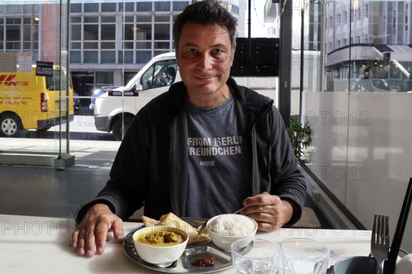 Man in a restaurant in Wellington enjoying a meal with an urban background, Wellington, North Island, New Zealand